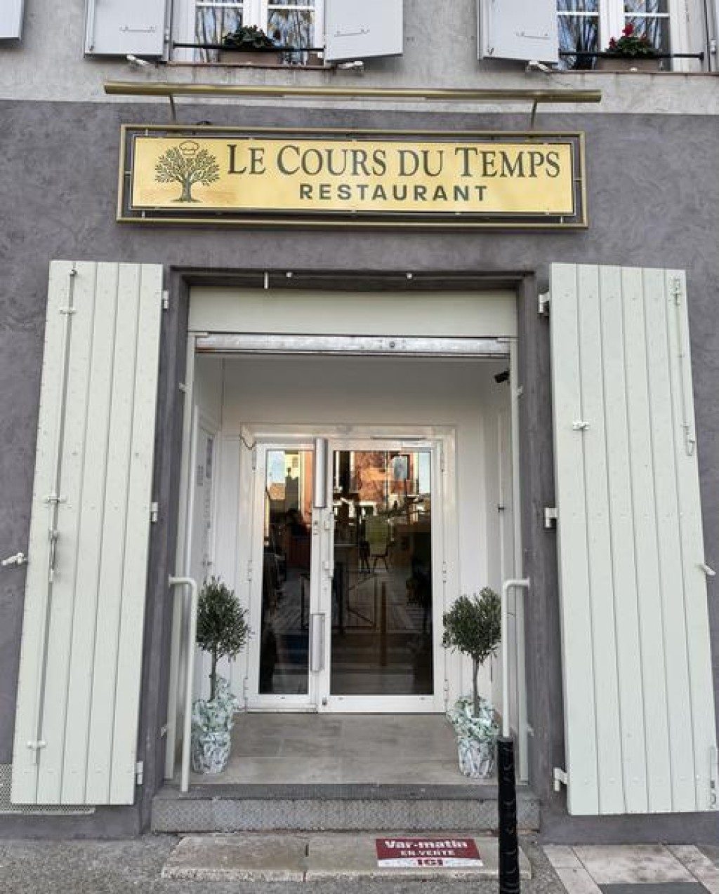 La façade du restaurant : enseigne dorée « Le Cours du Temps – Restaurant », volets vert pâle, porte vitrée