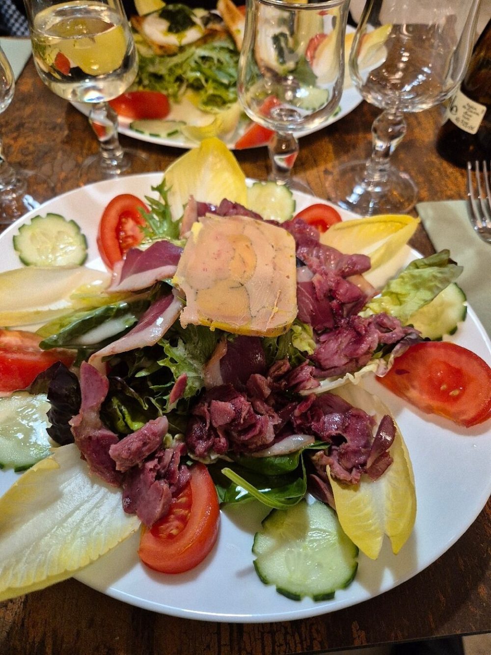 Une grande salade composée, avec de fines tranches de viande séchée, de la tomate et du concombre