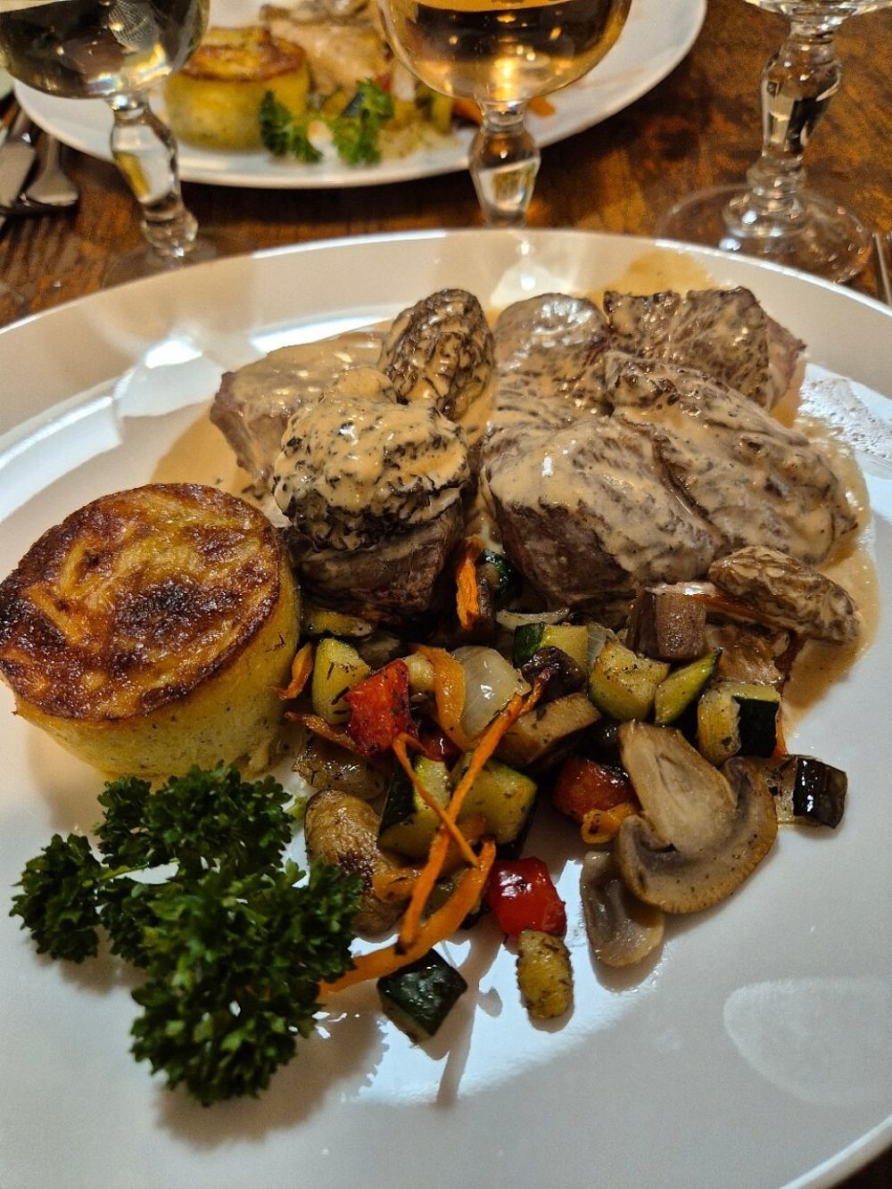 Des tranches de viande avec une pomme de terre gratinée, des légumes grillés et du persil
